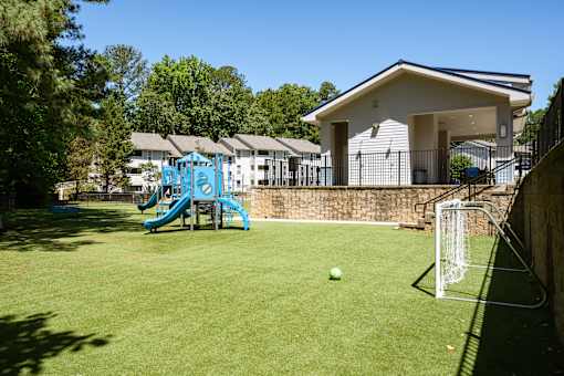 A soccer ball is in front of a goal on a green field.