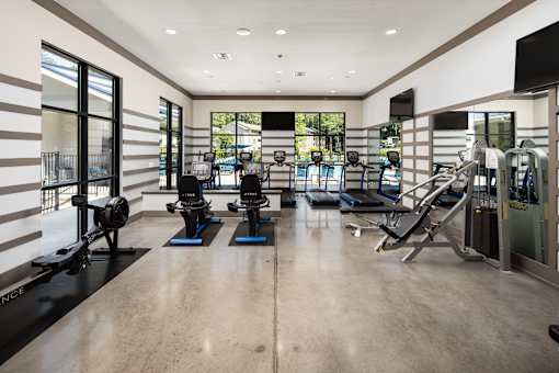 A gym with a variety of equipment including treadmills, stationary bikes, and weight machines.