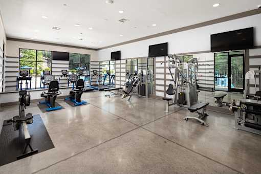 A gym with a variety of equipment including treadmills, weights, and exercise machines.