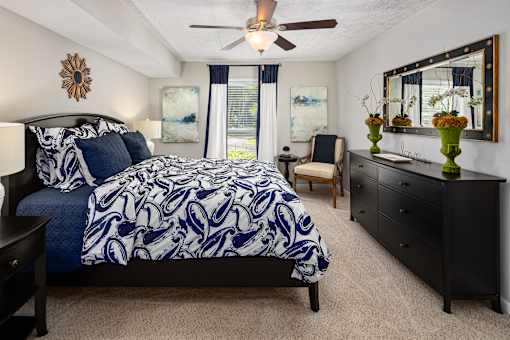 A bedroom with a large bed and a ceiling fan.