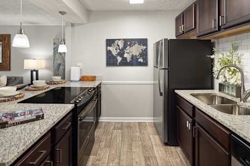A kitchen with a black fridge and wooden floors.
