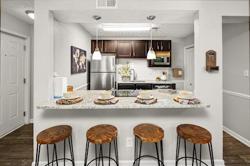 A kitchen with a granite countertop and bar stools.