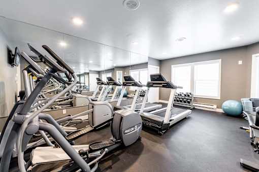 A gym with treadmills, elliptical machines, and a ball.