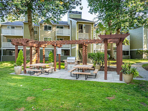 A patio with a pergola and benches is surrounded by apartment buildings.