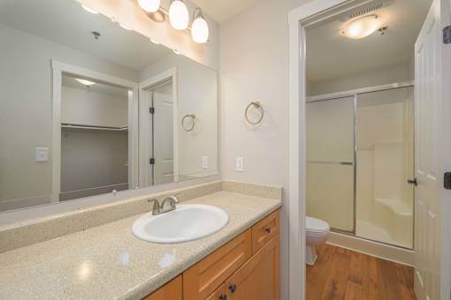 A bathroom with a sink, mirror, toilet and shower.