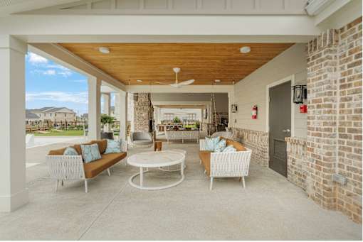 A patio with a white table and chairs and a brick wall.