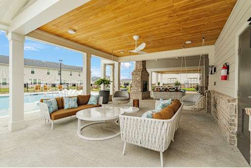 A patio with a white wicker sofa and a table with a fan.
