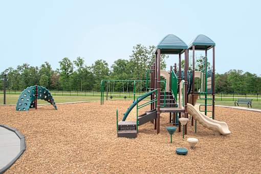 A playground with a green slide and a brown wooden structure at Willow Creek Apartment, Kalamazoo, MI, 49008