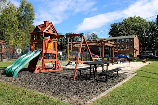 A playground with a green slide and a red wooden playhouse.