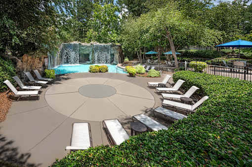 A pool surrounded by a circular patio with lounge chairs.