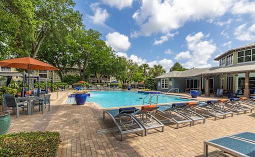A pool area with sun loungers and a building in the background.