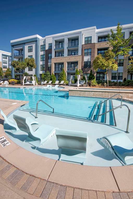 A swimming pool with a slide in front of apartment buildings.