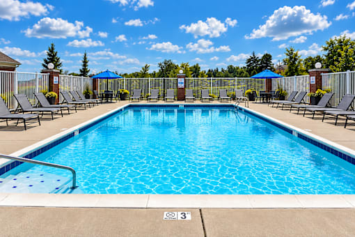A large outdoor swimming pool surrounded by lounge chairs and umbrellas.