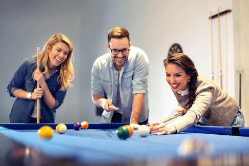 Three people playing pool together.