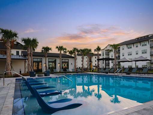 A swimming pool surrounded by palm trees and buildings.