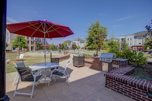 A red umbrella is on a patio table with chairs.