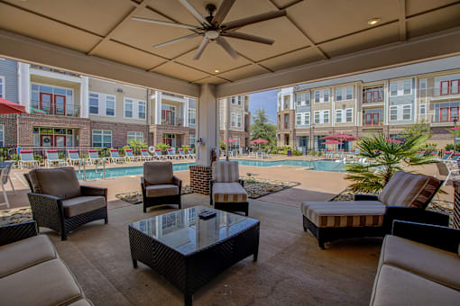 A patio with a table, chairs, and a pool in the background.
