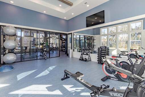 A gym with a variety of equipment including a stationary bike and a rowing machine.