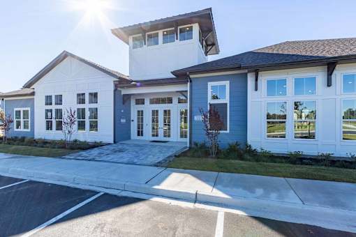 A modern two-story building with a parking lot in front.