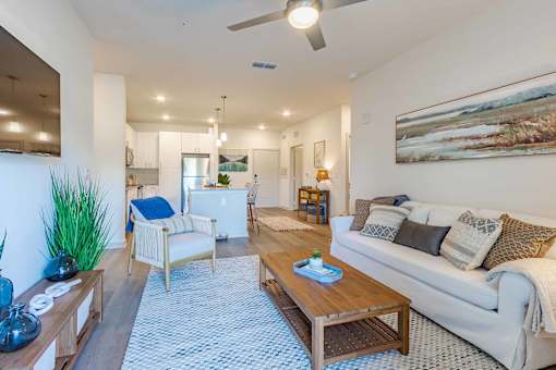 A living room with a white couch, a wooden coffee table, and a painting on the wall.