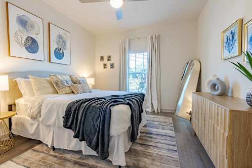 A bedroom with a bed, a dresser, and a ceiling fan.