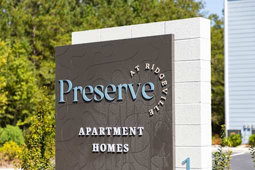 a sign for preserve apartment homes in front of trees