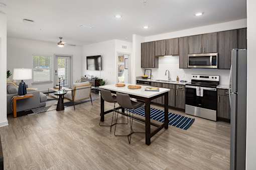 Dog-Friendly Luxury Apartments in Ridgeville, SC - Preserve at Ridgeville - Modern Kitchen With Dark Wood Cabinets, Stainless Steel Appliances, And Large Island Dining Table.