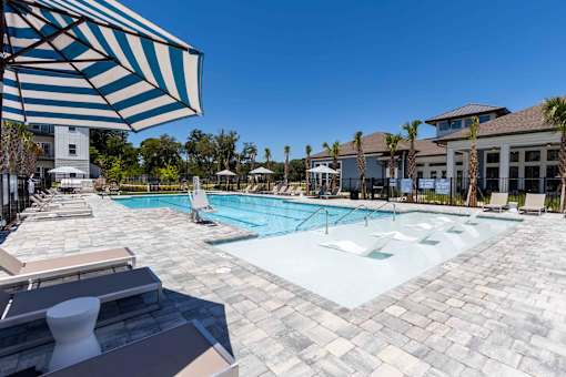 A large outdoor swimming pool surrounded by lounge chairs and umbrellas.