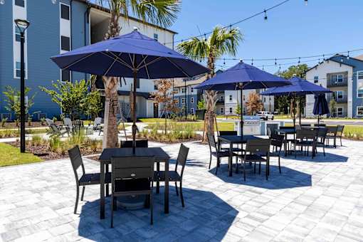 A patio with tables and chairs and umbrellas.