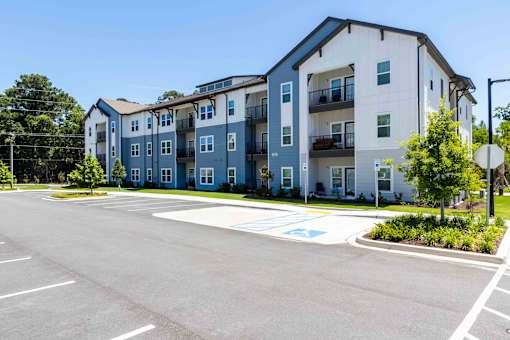 A large apartment complex with a parking lot in front.