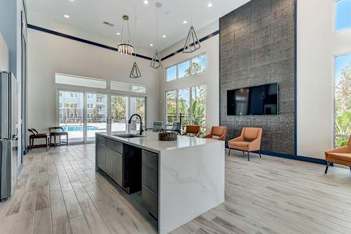 A modern kitchen with a large island and a refrigerator on the left.