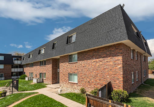 A red brick house with a black roof and a small fence in front.