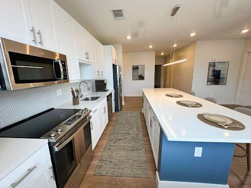 A kitchen with white cabinets and a blue island.
