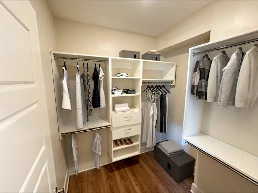 A walk in closet with clothes hanging and shelves.