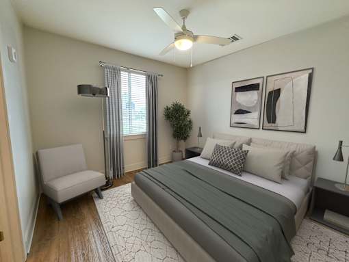 A bedroom with a bed, chair, and a ceiling fan.