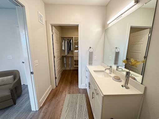 A bathroom with a vanity, mirror, and a chair.