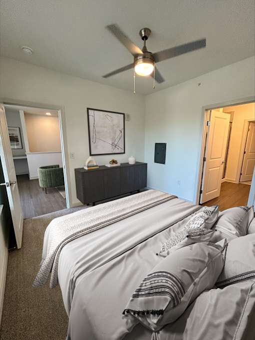A bedroom with a bed in the center and a ceiling fan above it.