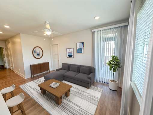 A living room with a grey couch, a wooden coffee table, and a ceiling fan.