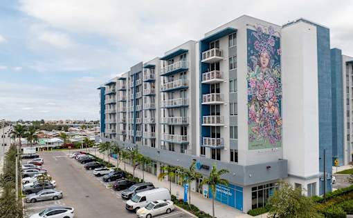 A large building with a mural on the side is surrounded by a parking lot.