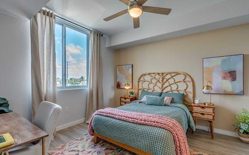 A bedroom with a bed, a chair, and a ceiling fan.