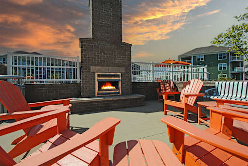 A fireplace is surrounded by red chairs and tables.