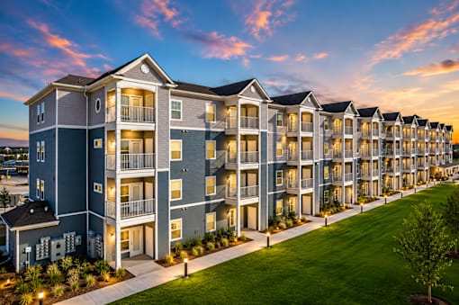 A long building with balconies is lit up at dusk.