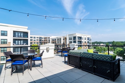 2-Bedroom Luxury Apartments in Decatur, GA - Reserve Decatur - Rooftop Entertainment Lounge with Tables and Chairs, Couch, Cafe Lights, and Expansive Views.