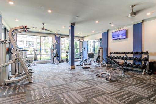 a gym with weights and other exercise equipment in a building with glass doors