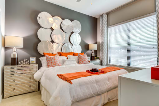 a bedroom with a white bed and orange pillows