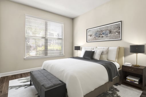 Upscale Apartments in Decatur, GA - Reserve Decatur - Bedroom with Designer Plank Flooring, Area Rug, Full-Size Bed, Nightstands with Lamps, Wall Art, and Large Window with Blinds.