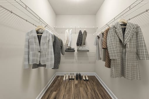 a walk in closet with coats and jackets and wooden floors
