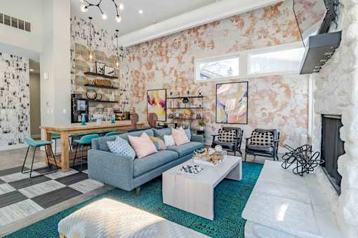 A living room with a grey couch and a white fireplace.