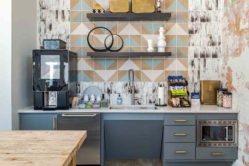 A kitchen with a wooden table in front of a blue and white tiled wall.