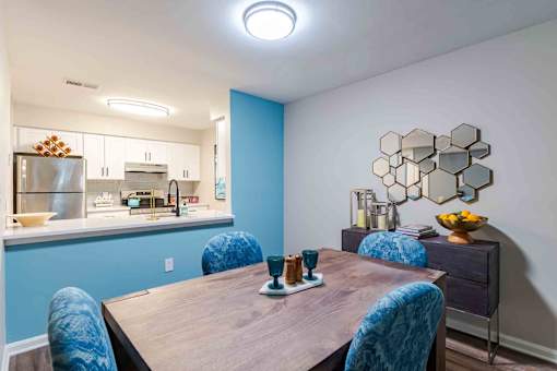 A kitchen with blue walls and a wooden table with blue chairs.